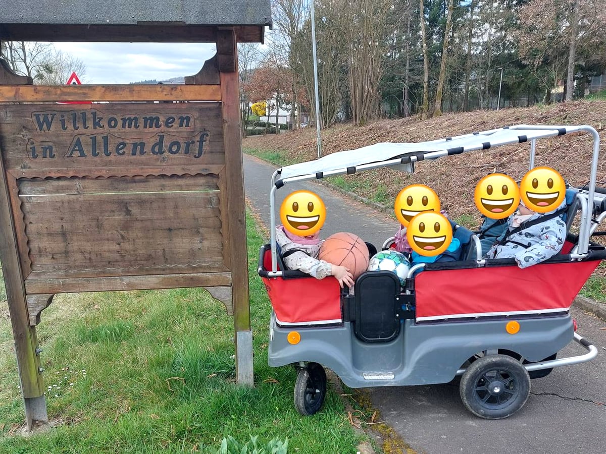 Kinder im Ausflugswagen am Ortsschild Allendorf, Gesichter unkenntlich gemacht